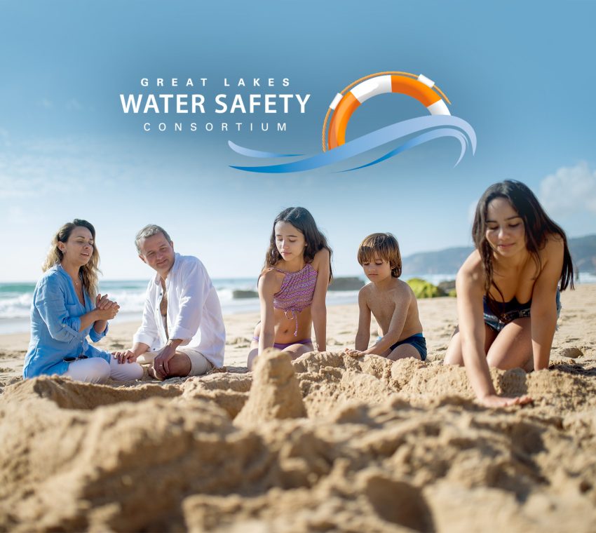 Family playing in beach sand safely thanks to SwimSmart and the Great Lakes Water Safety Consortium
